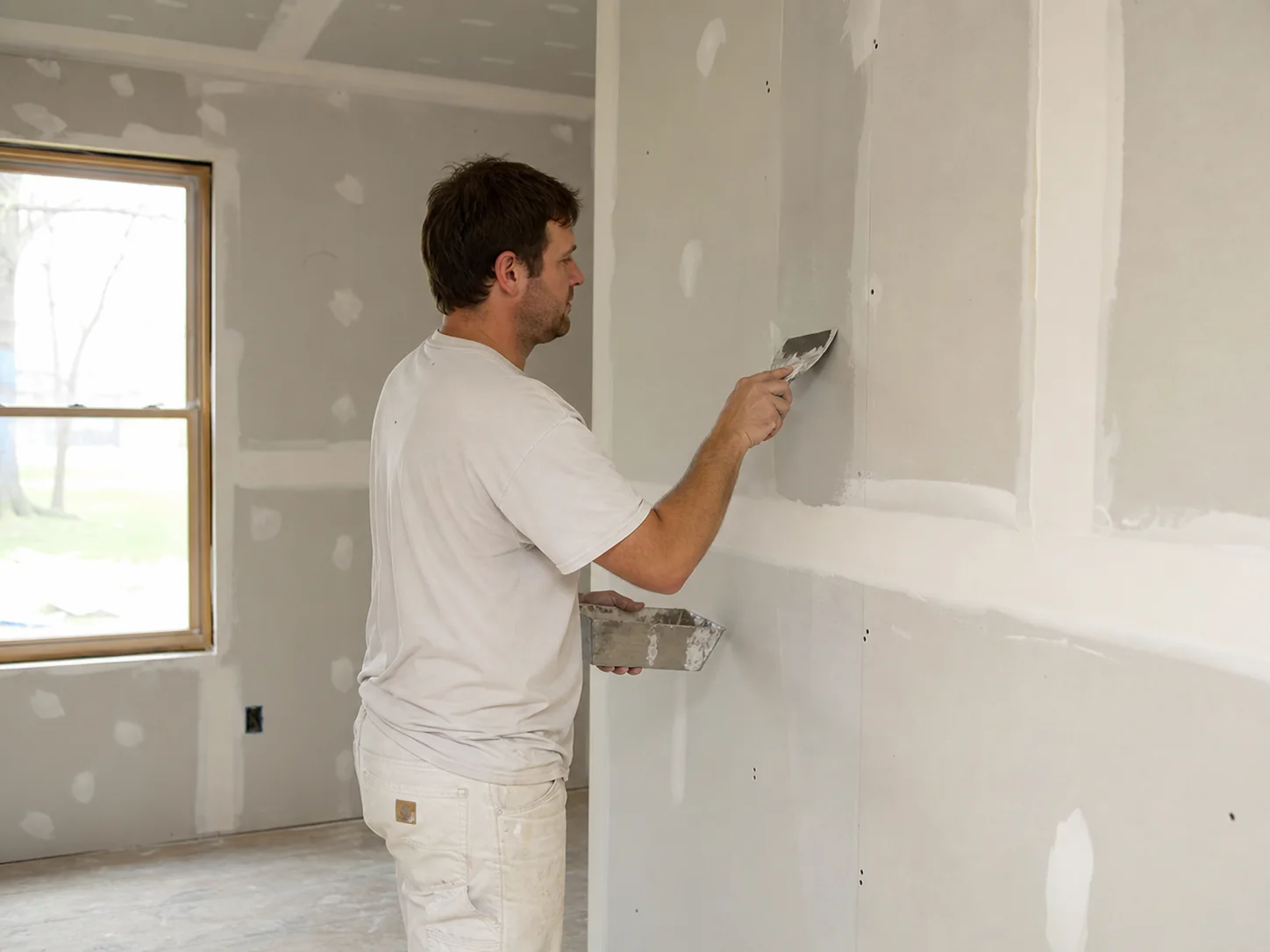 Craftsperson applying joint compound to drywall